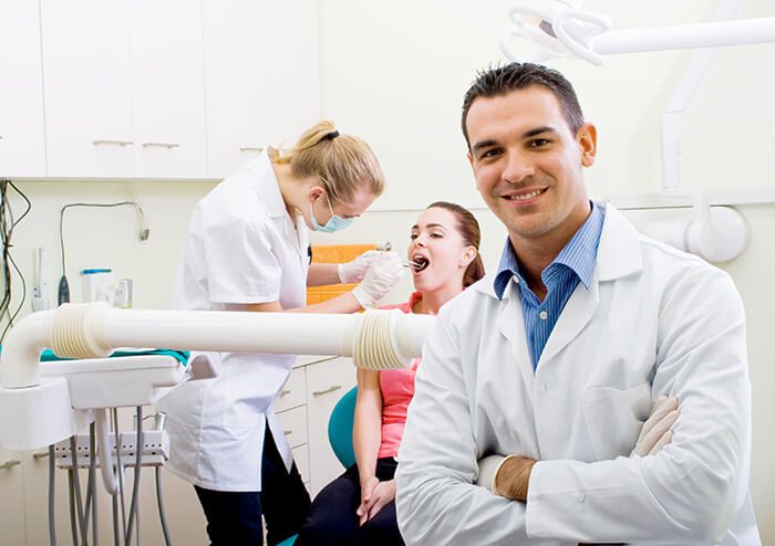 SD Dentists Smiling, patient getting checked in the background